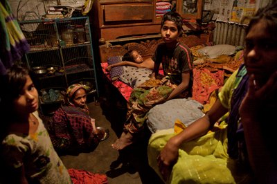 A family, in the bamboo slum housing, near Buriganga river, in Old Dhaka, Bangladesh. February 21, 2007. As many as 6 to 10 people live in 10 feet by 10 feet rooms, and share communal hand pump, toilet and kitchen between them. Most people living in such h by Unbekannt Unbekannt